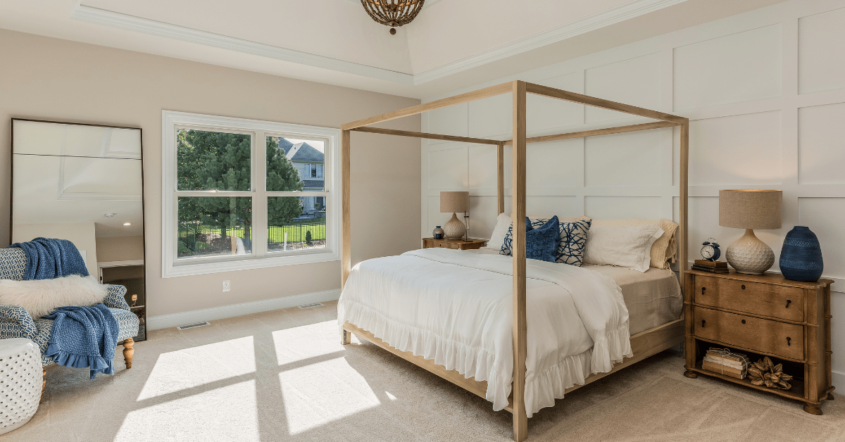 Modern bedroom with a light wooden four poster bed.