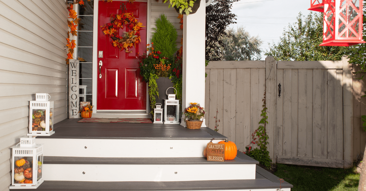 Fall front yard decor with white lanterns filled with pumpkins.