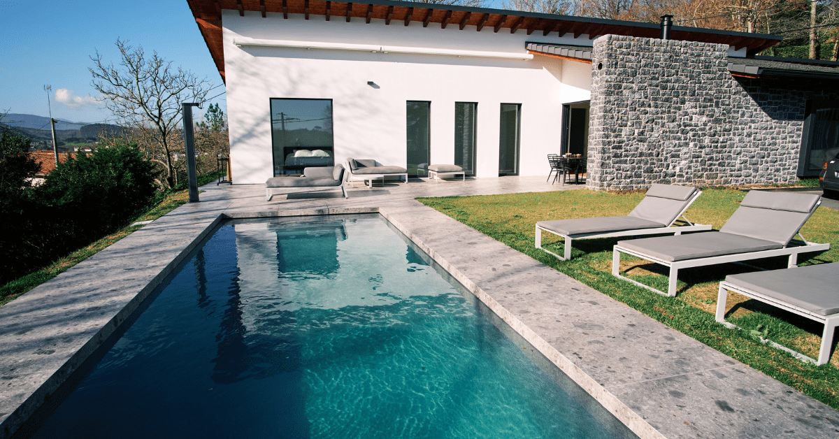 Backyard with pool and lounging chairs.