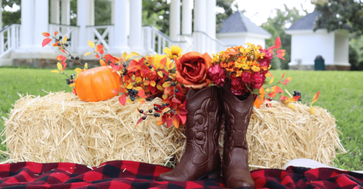 Pumpkins used as front yard decor on top of a hay stack.