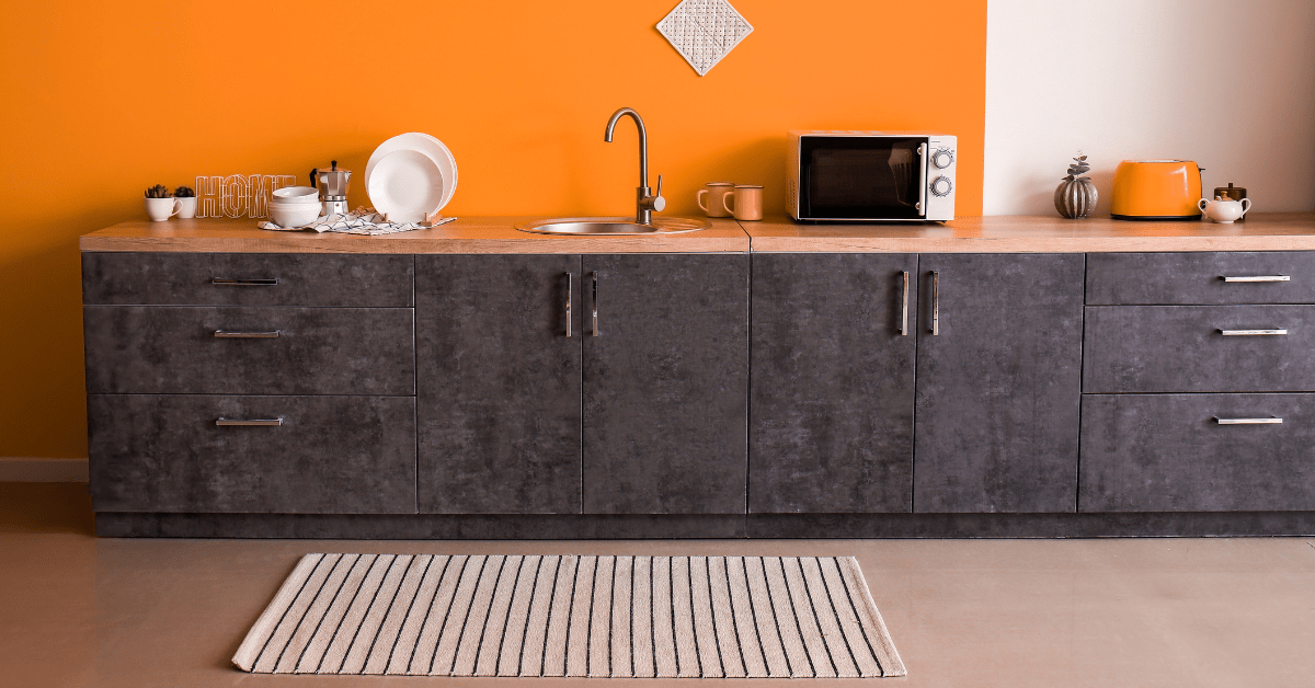 Orange wall in a kitchen with dark cabinets.