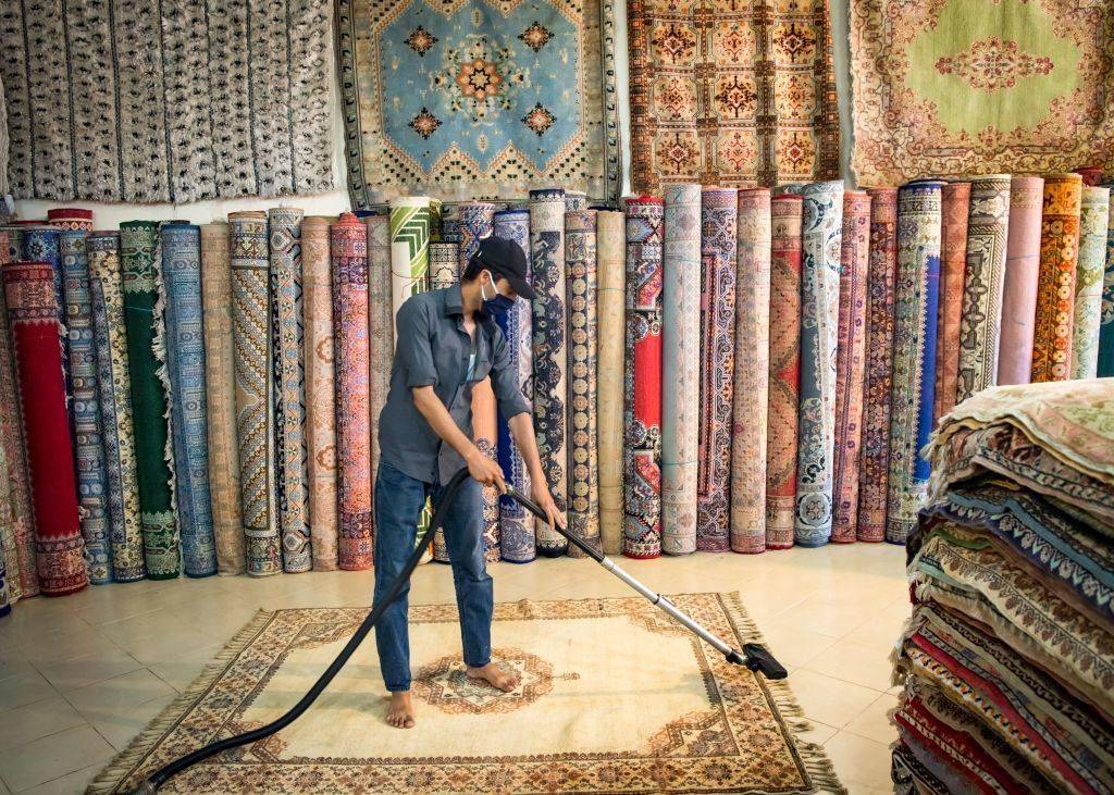 Moroccan rug dealer cleans a carpet at a shop in the city of Sale, north of the capital Rabat, on June 3, 2020, during the novel coronavirus pandemic