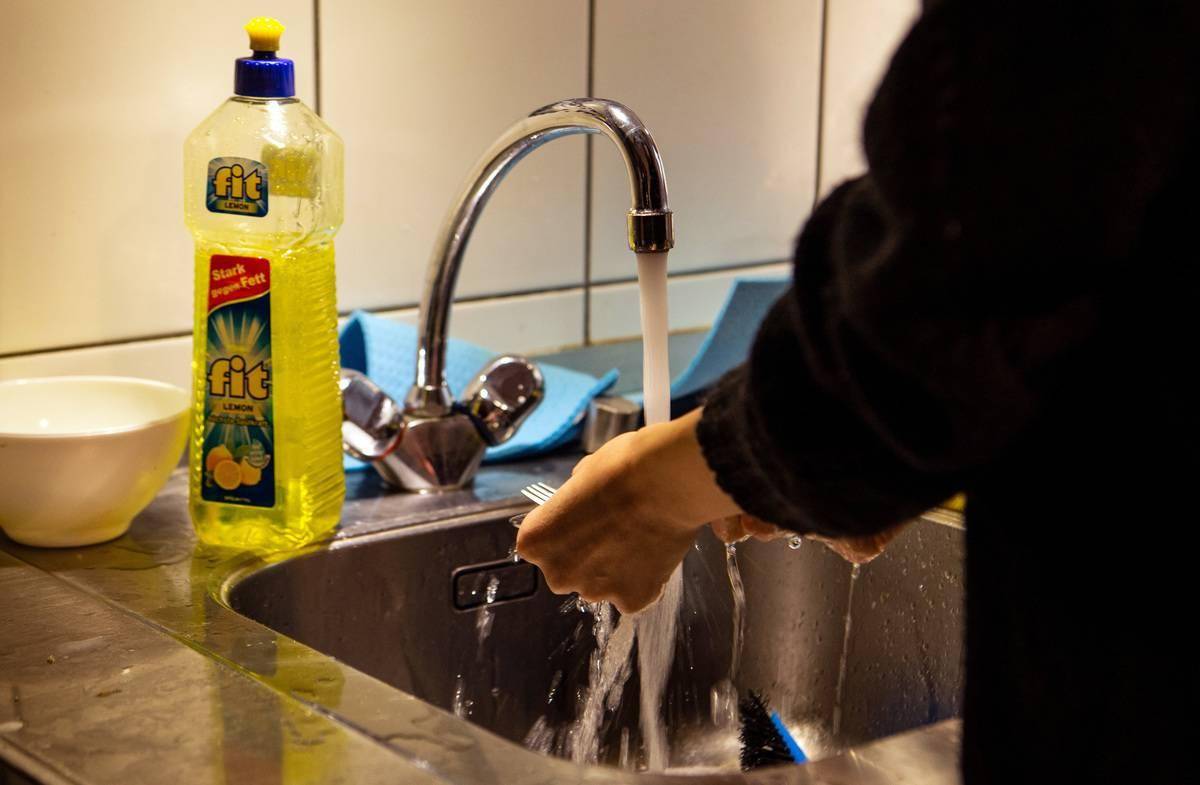 person doing dishes by hand at sink