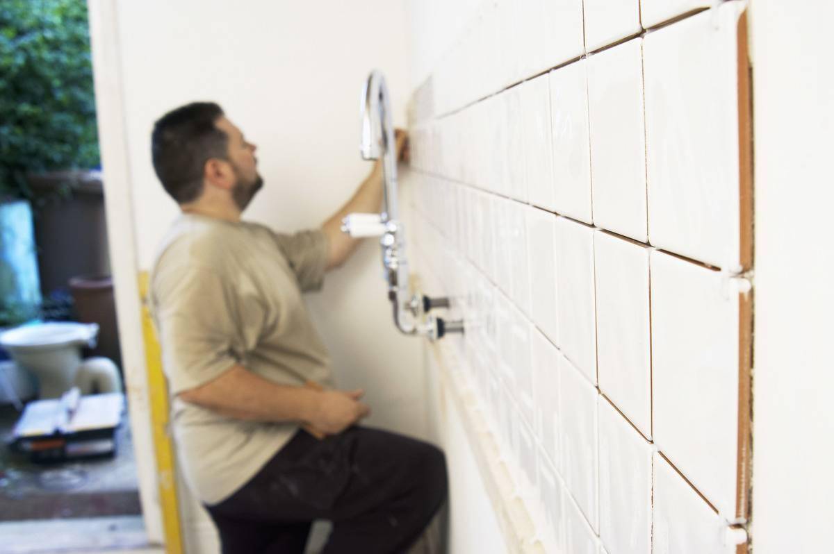 man tiling bathroom