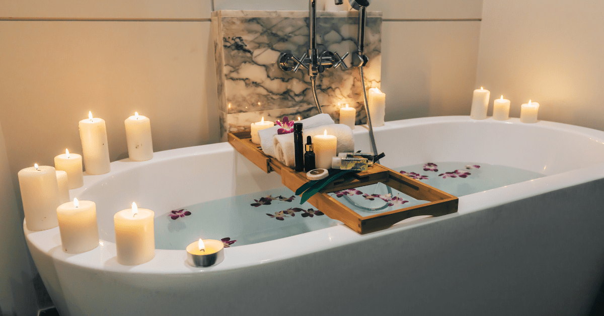 Large white bathroom tub with candles on the edge.