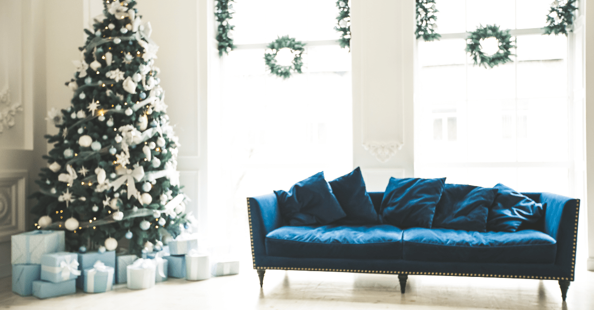 Blue velvet couch with Christmas tree in a living room.