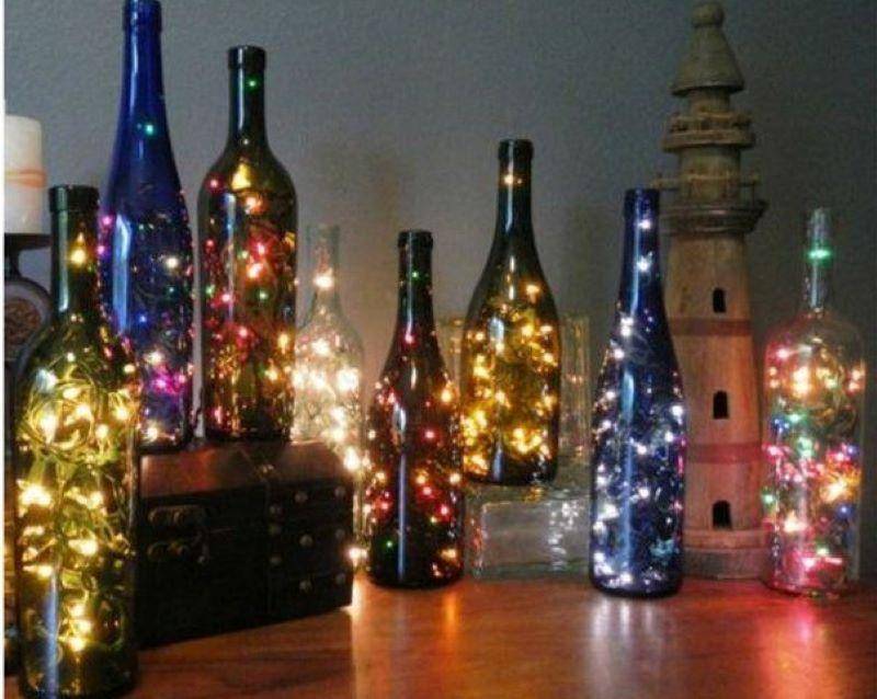 White bottles wrapped in Christmas lights.