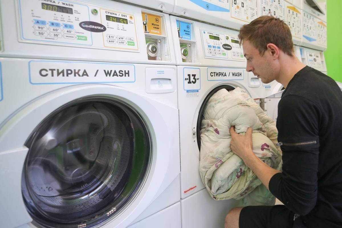 A man pushes laundry into a washing machine.