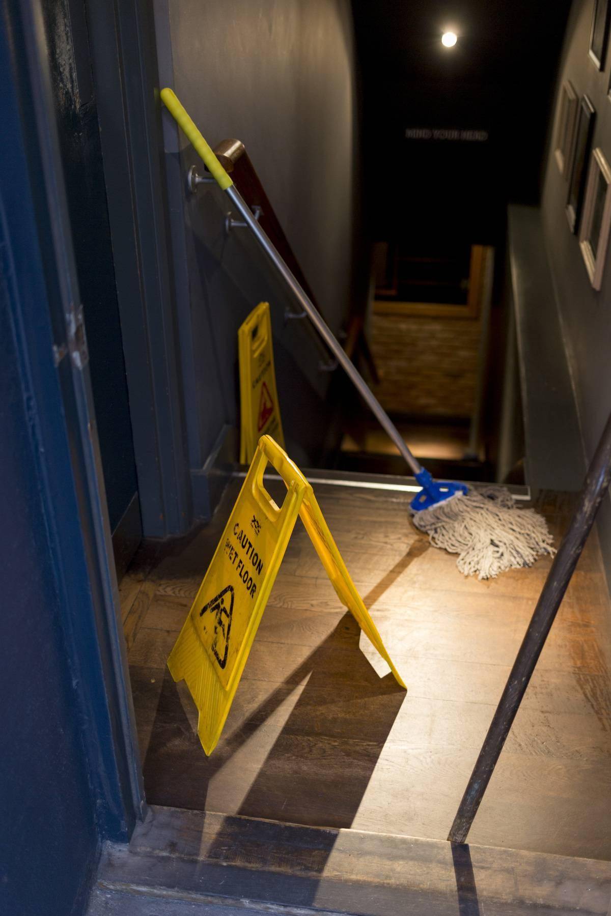 A string mop leans against a wall.