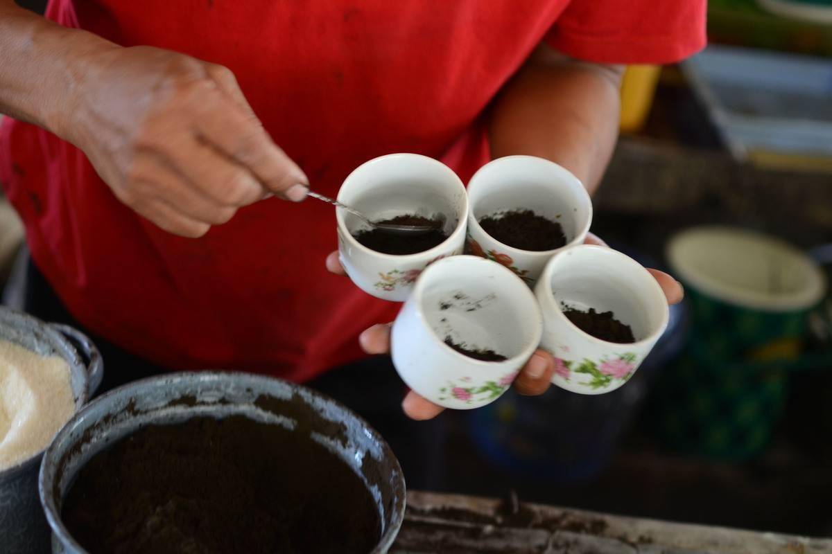 A man dishes coffee grounds from cups.