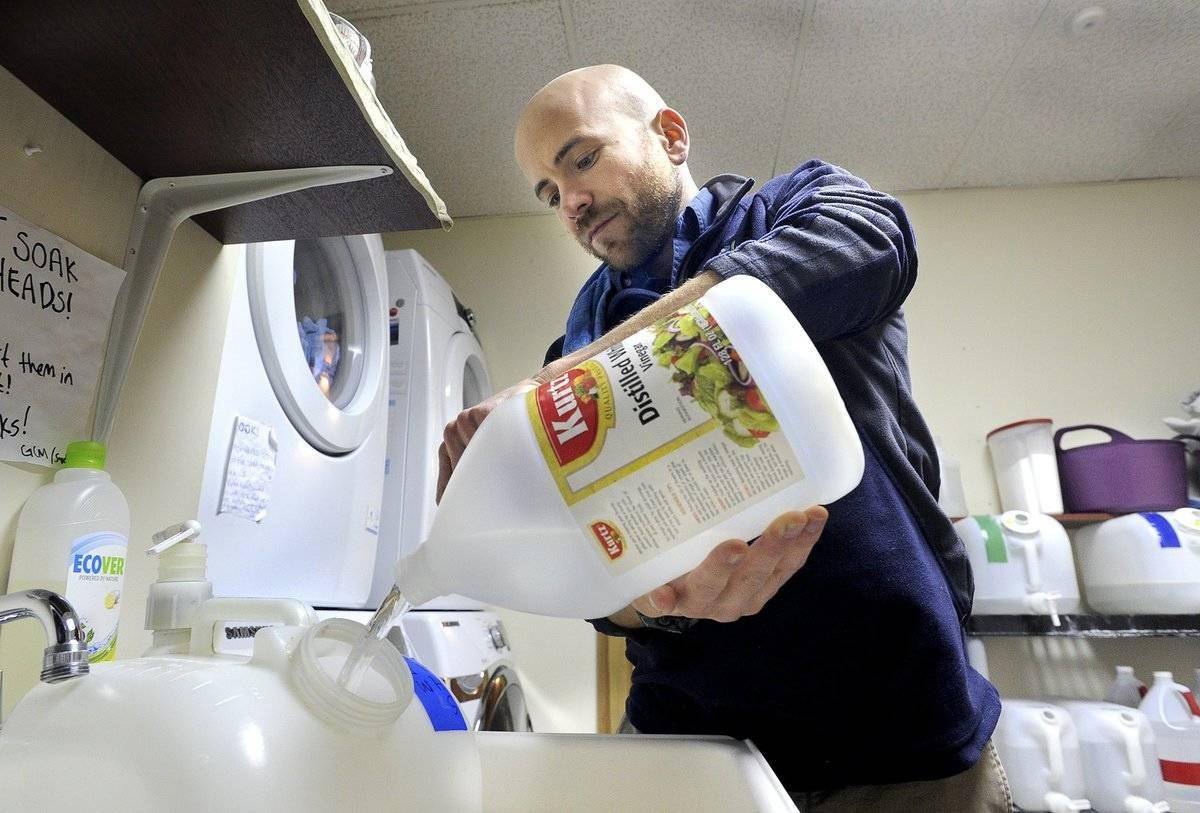 A man pours vinegar into water to clean.