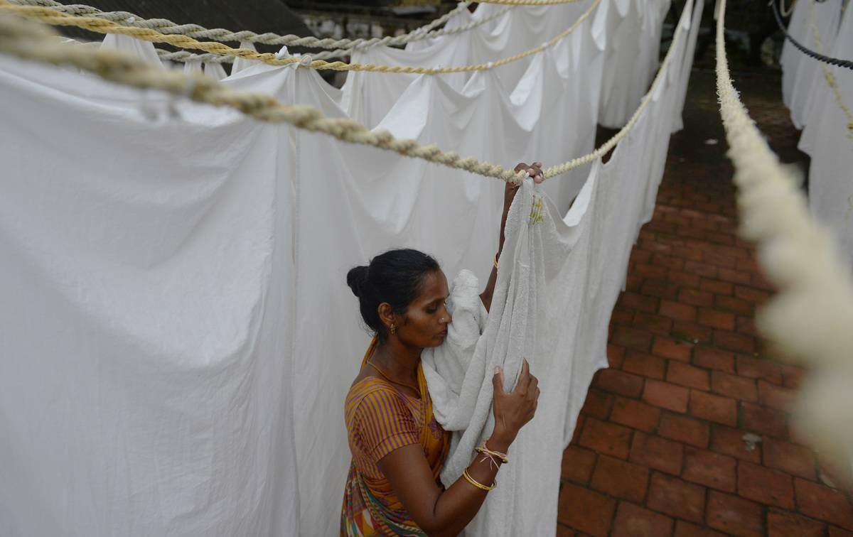 A woman hangs bed sheets to dry in India.