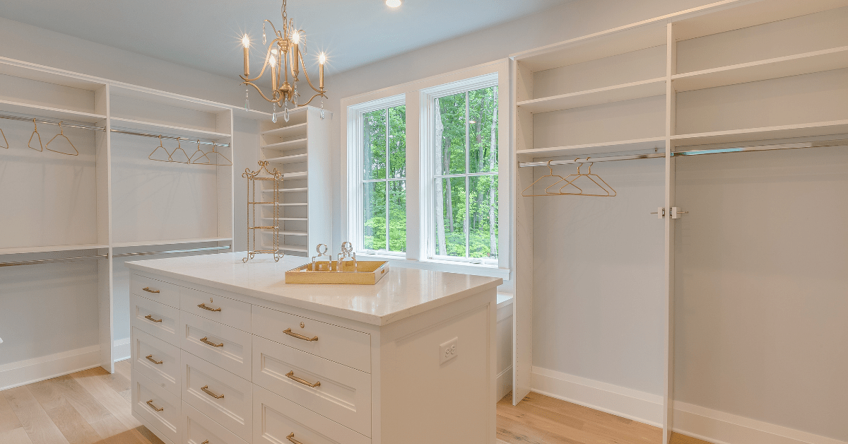 Empty closet with an island, all finished in white.