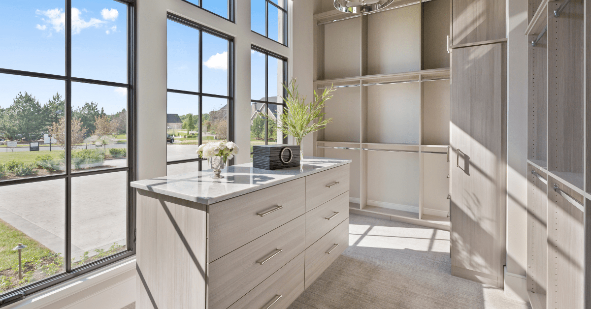 Empty closet with an island in the middle flanked by large windows.