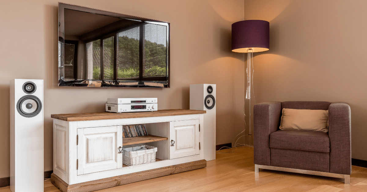 A wall-mounted TV and corner sitting chair, flanked by a room light.