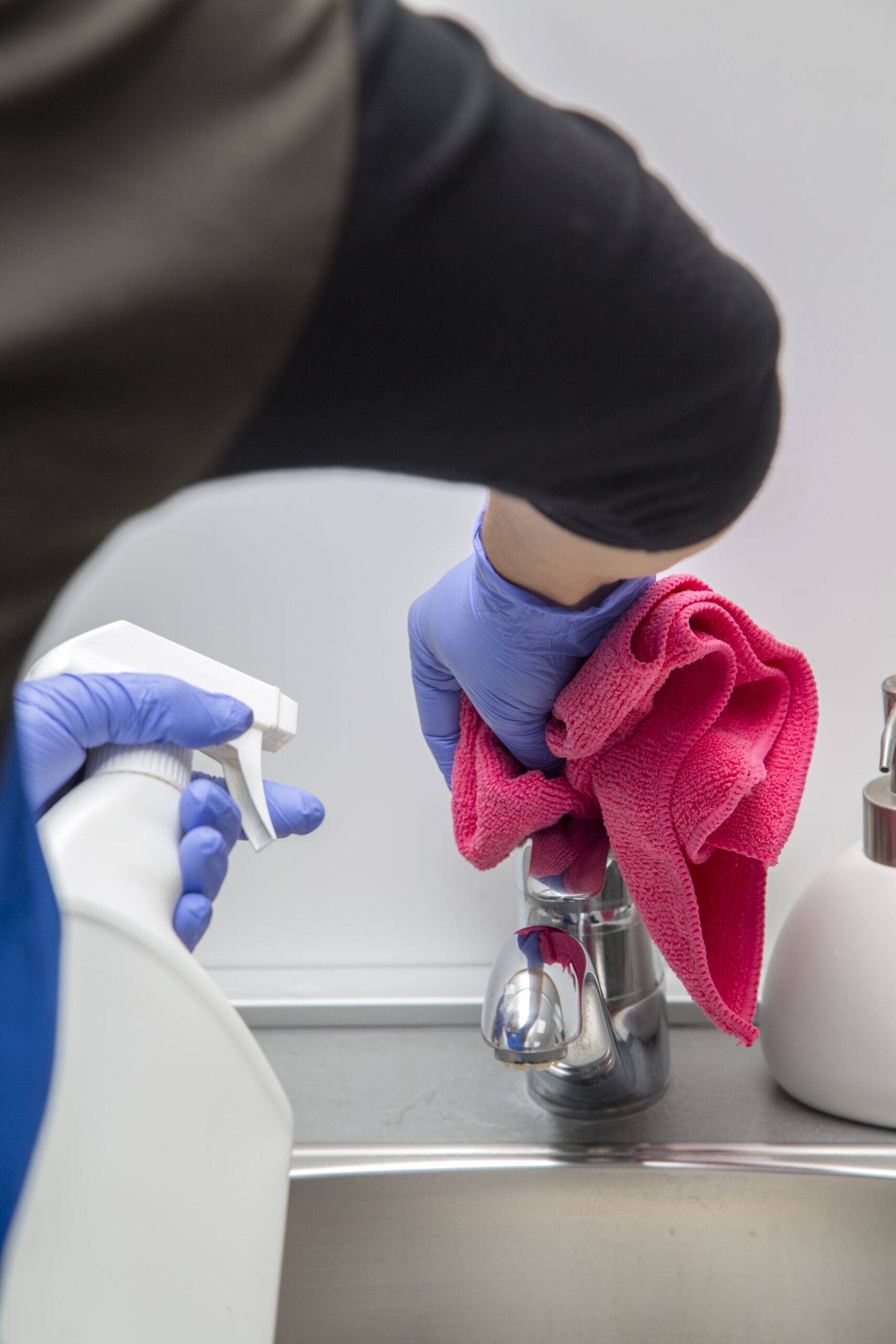 Someone cleaning a bathroom sink faucet.