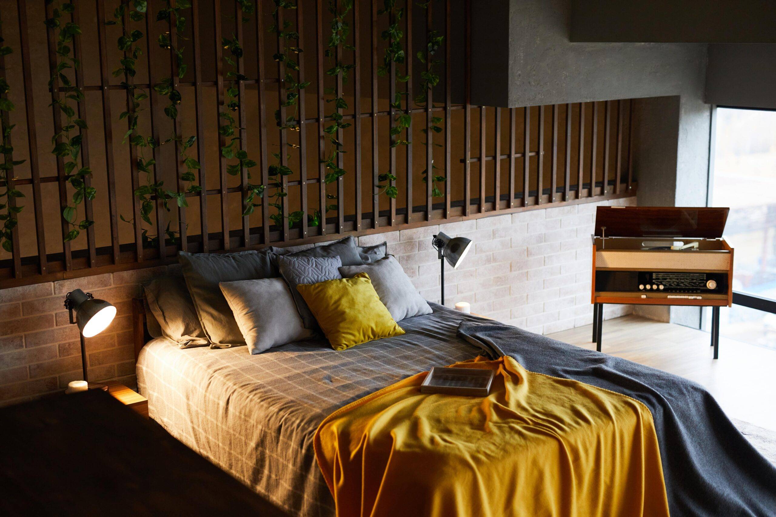 An above angle photo of a bed with table lamps on either side, vines on the wall behind it.