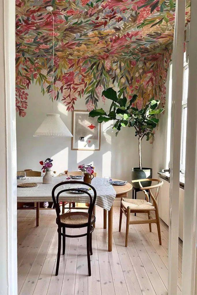 A view into a dining room with a floral mural on the ceiling.