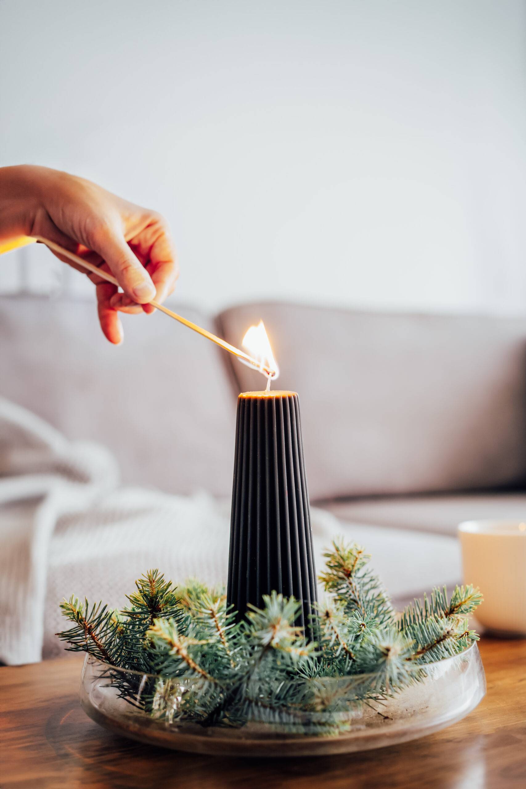 A hand lighting a tall candle.