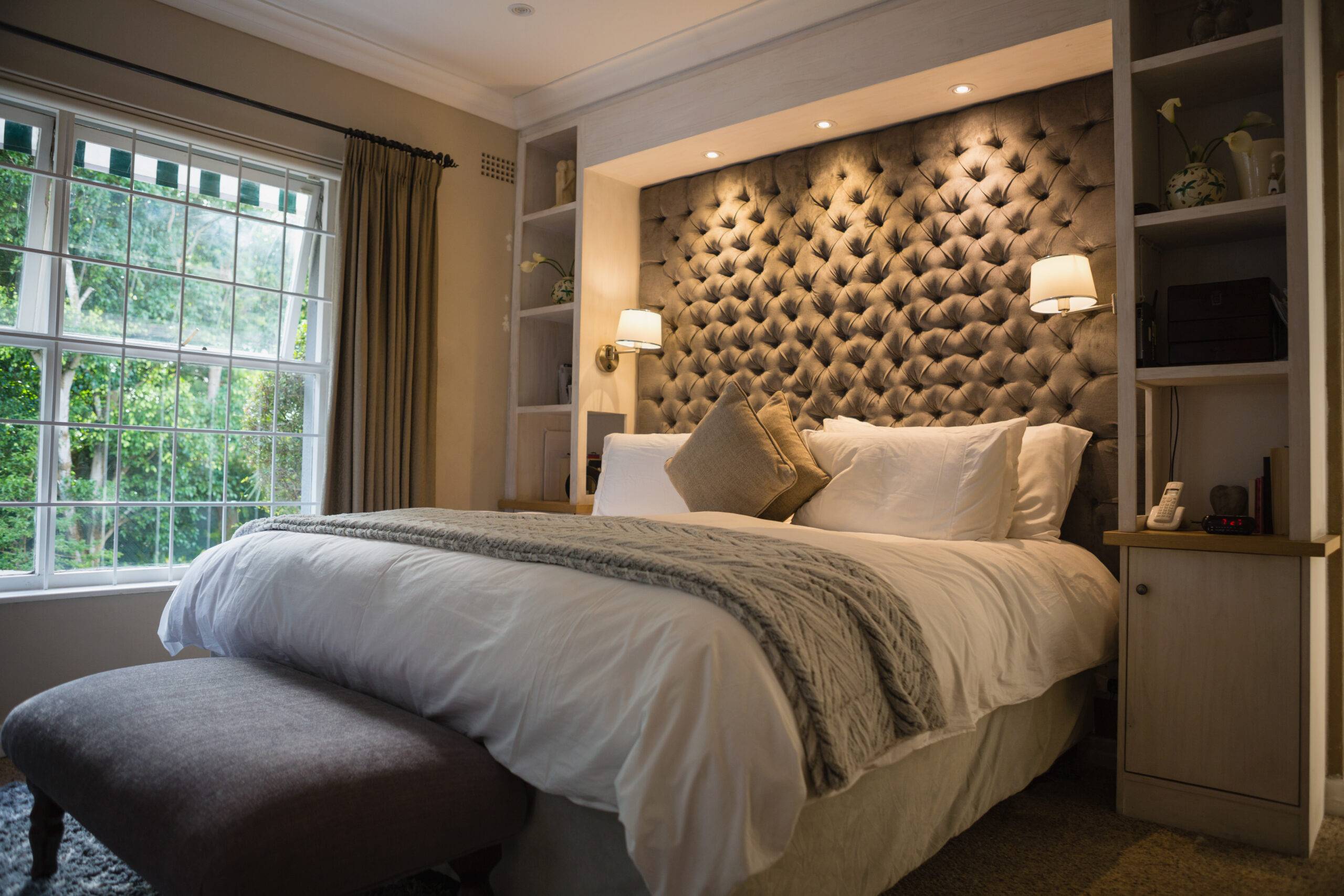 A grey palette bedroom with a velvet accent wall behind it, a large knit throw blanket on it.