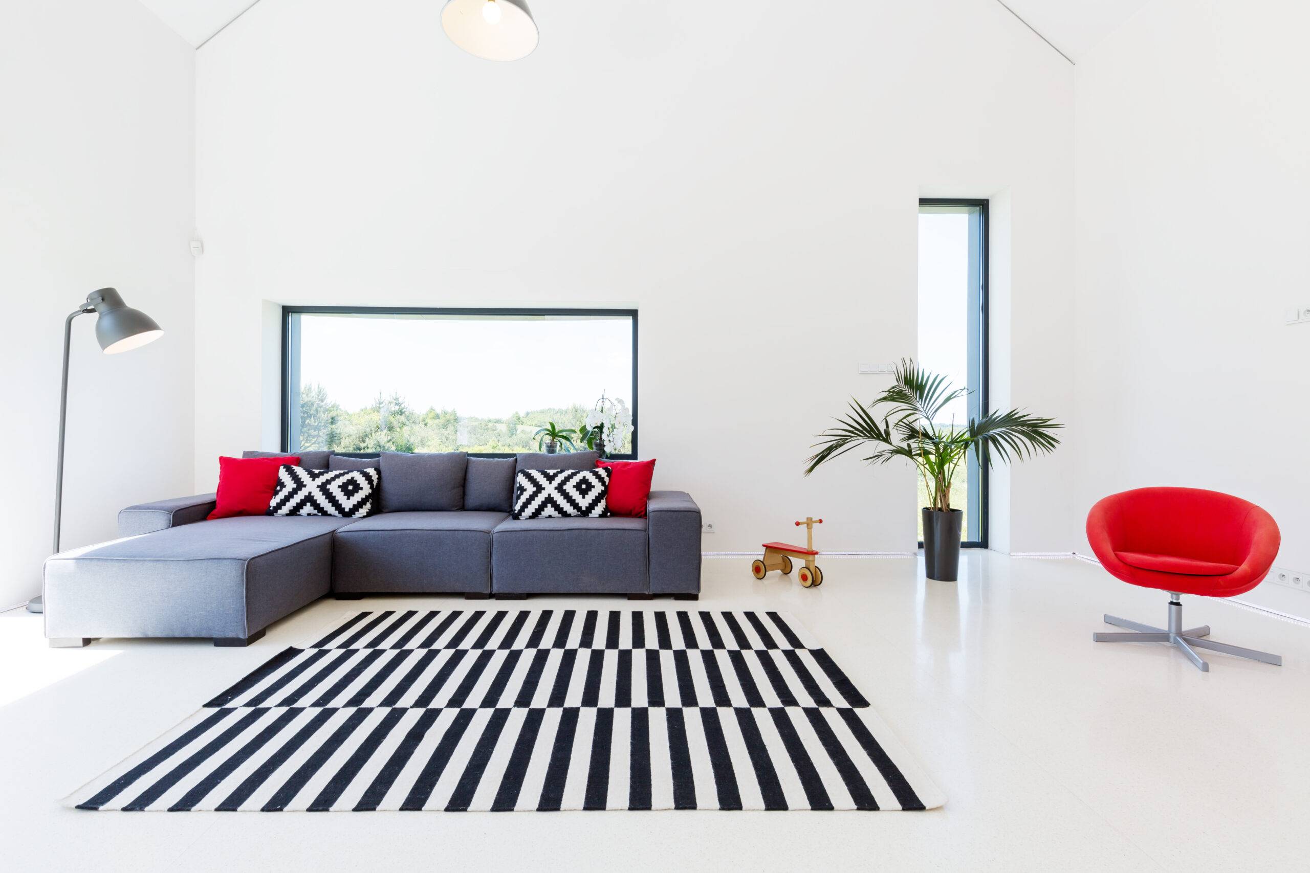 A modern living room with red accent pillows and chair.