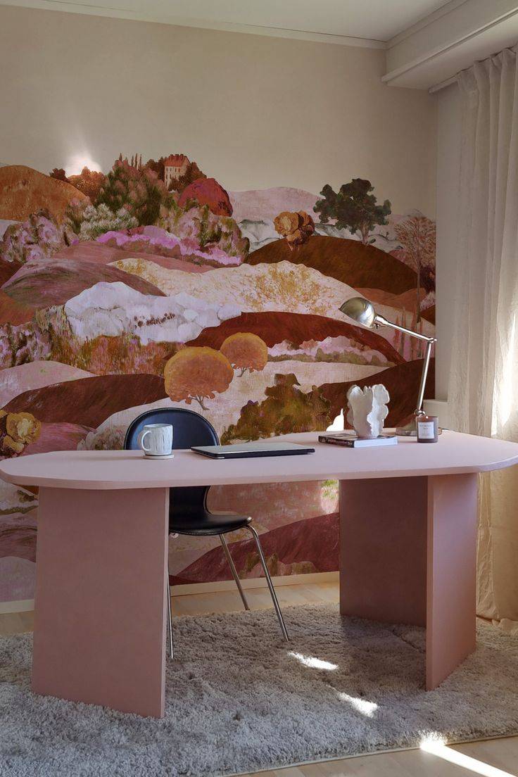 A pink office desk in front of a wall with a painted mural.