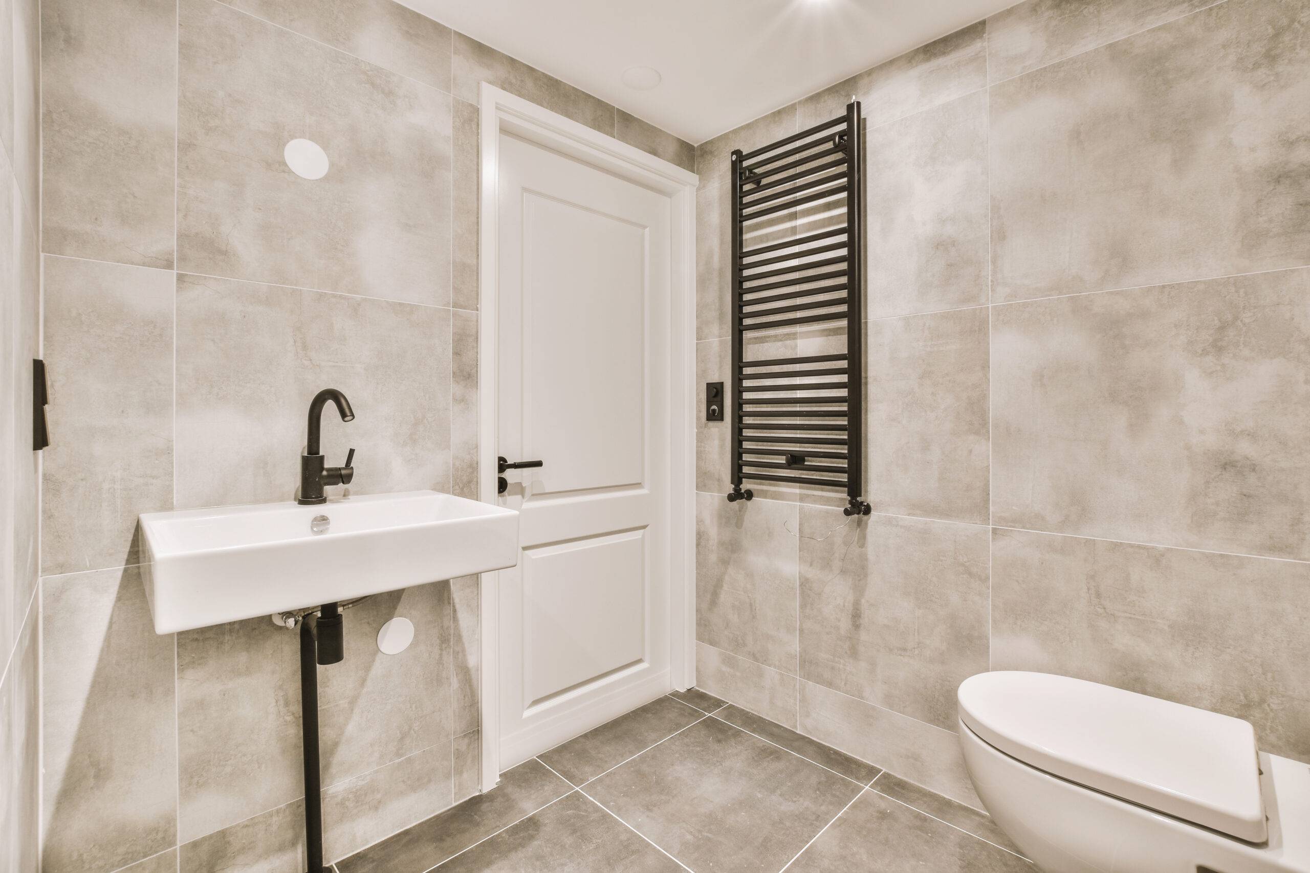 A bathroom with large tiles on the walls and floor.