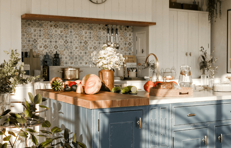 A French country kitchen with a blue island with a butcher block on top.