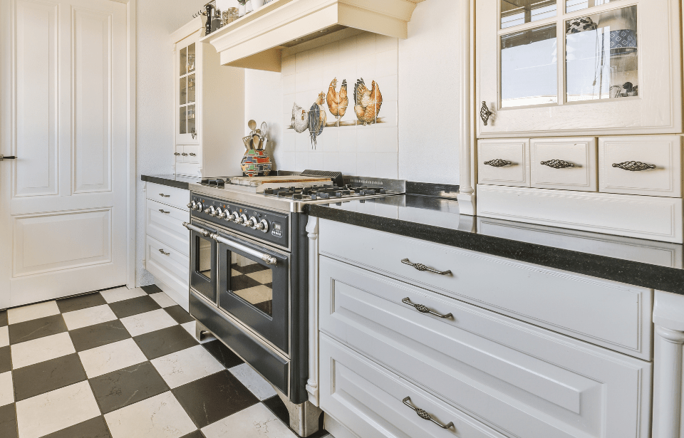 A close photo of a modern kitchen counter with ornate cabinets and handles.