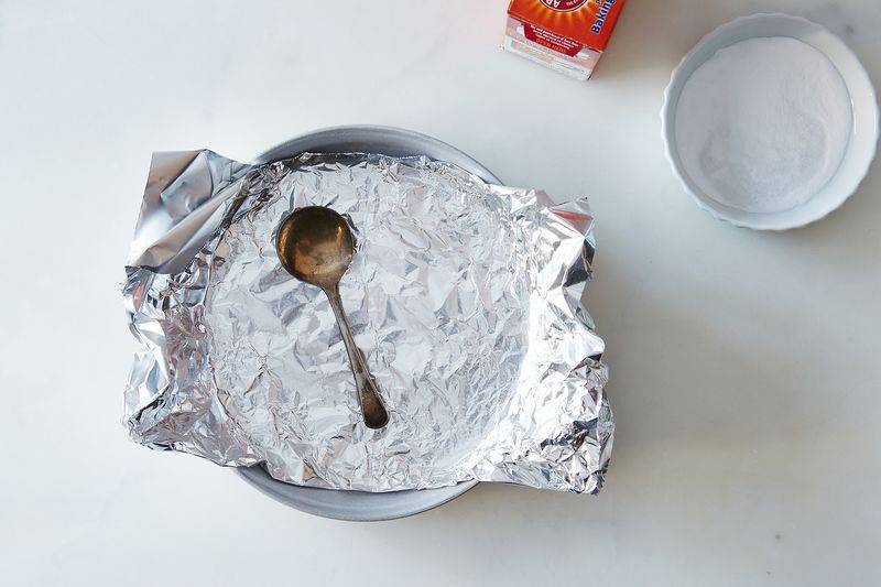 A tarnished silver spoon sitting in a pan lined with tin foil.