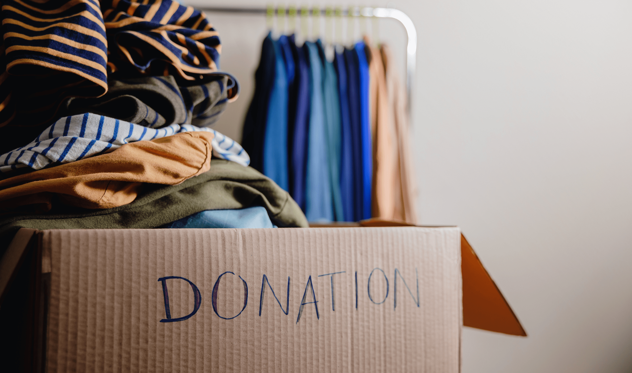 A close shot of a cardboard box full of clothes with "Donation" written on the side.