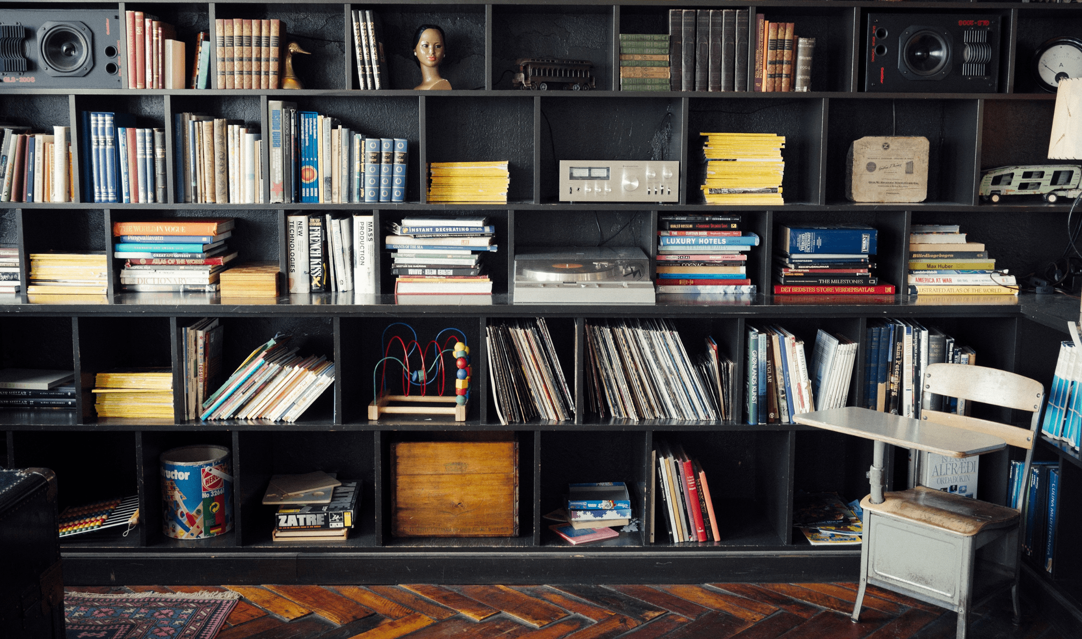 A large black bookshelf with a variety of objects on its shelves, a lot of visual diversity.