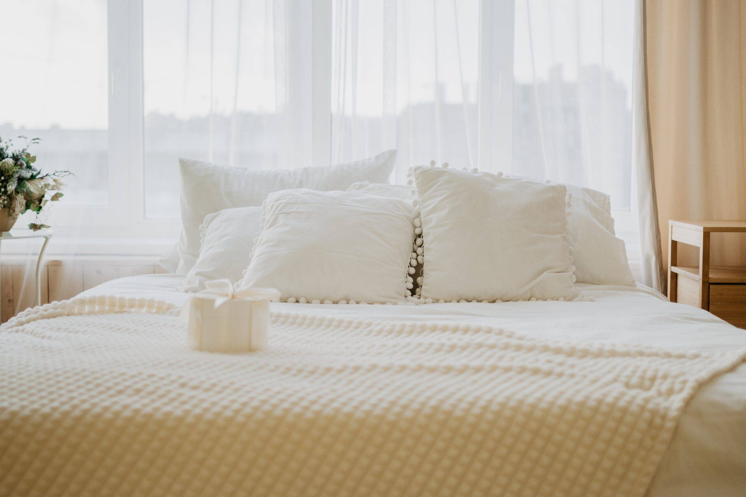 A bed with a soft, white, textured bedspread.