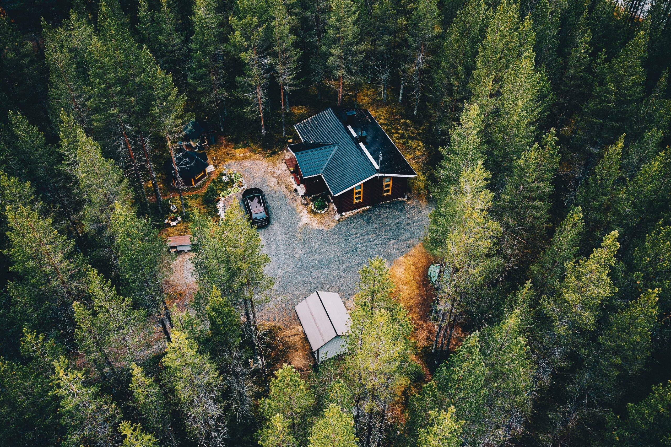 Aerial view of secluded cottage in the woods. Log cabin in the forest in rural Finland. View from above.