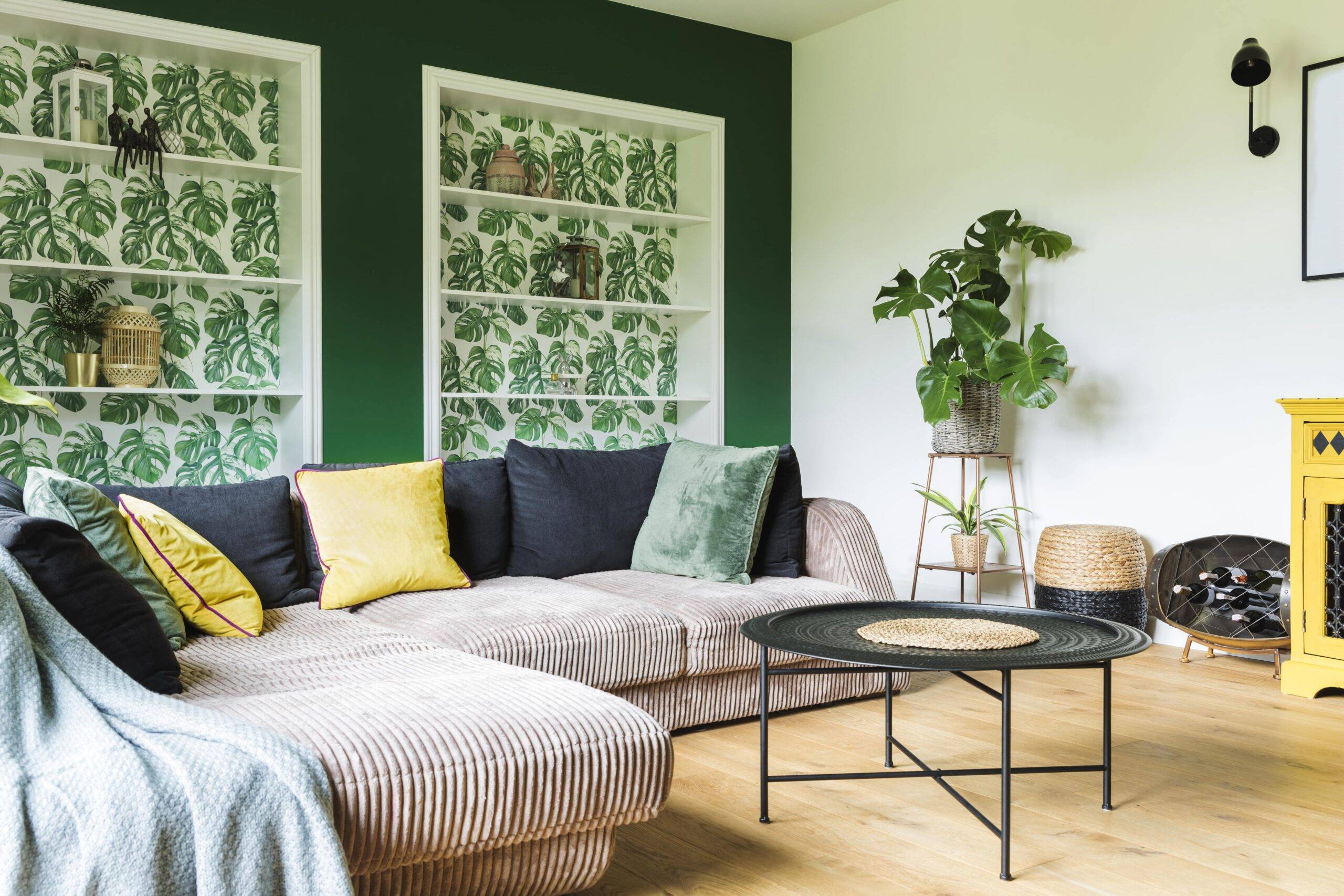 A living room with built-in bookshelves that have leaf-patterned wallpaper in them.