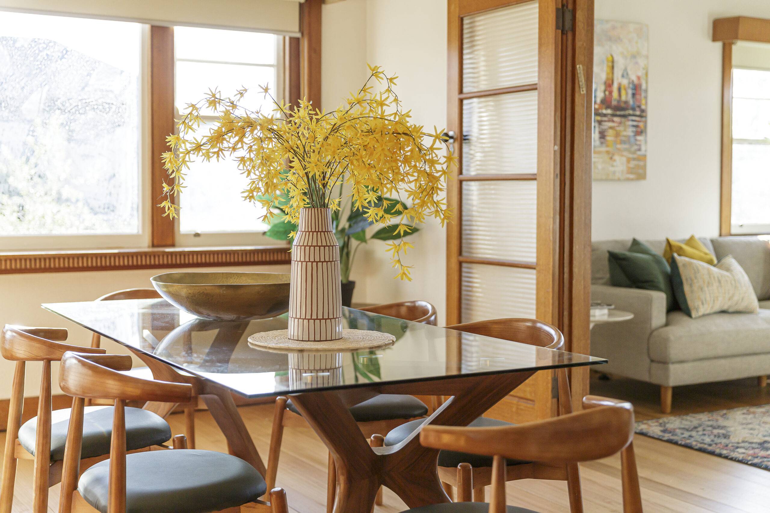 A glass-top dining table in a modern room with mid-century modern inspired design.