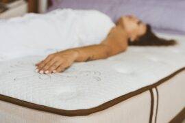 A woman laying on a bare mattress in a mattress store.