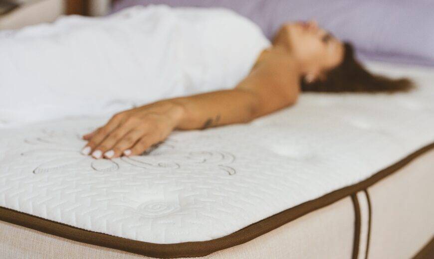 A woman laying on a bare mattress in a mattress store.