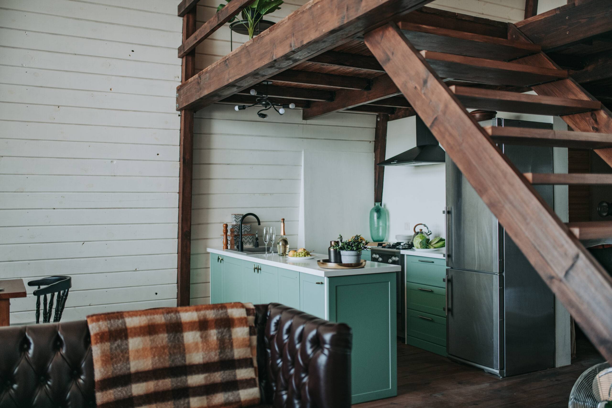 Interior of a tiny home, showing off the small kitchen space and loft above.