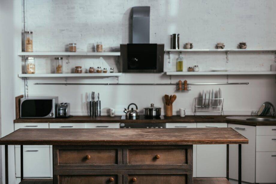 Une cuisine blanche avec une île en bois et en métal fini foncé.