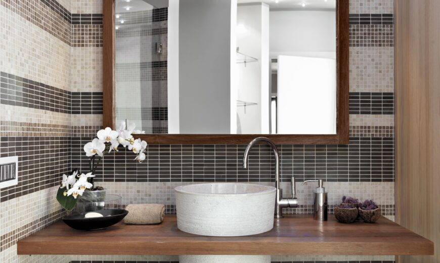 A bathroom vanity with a large, wood-framed mirror hanging above it.