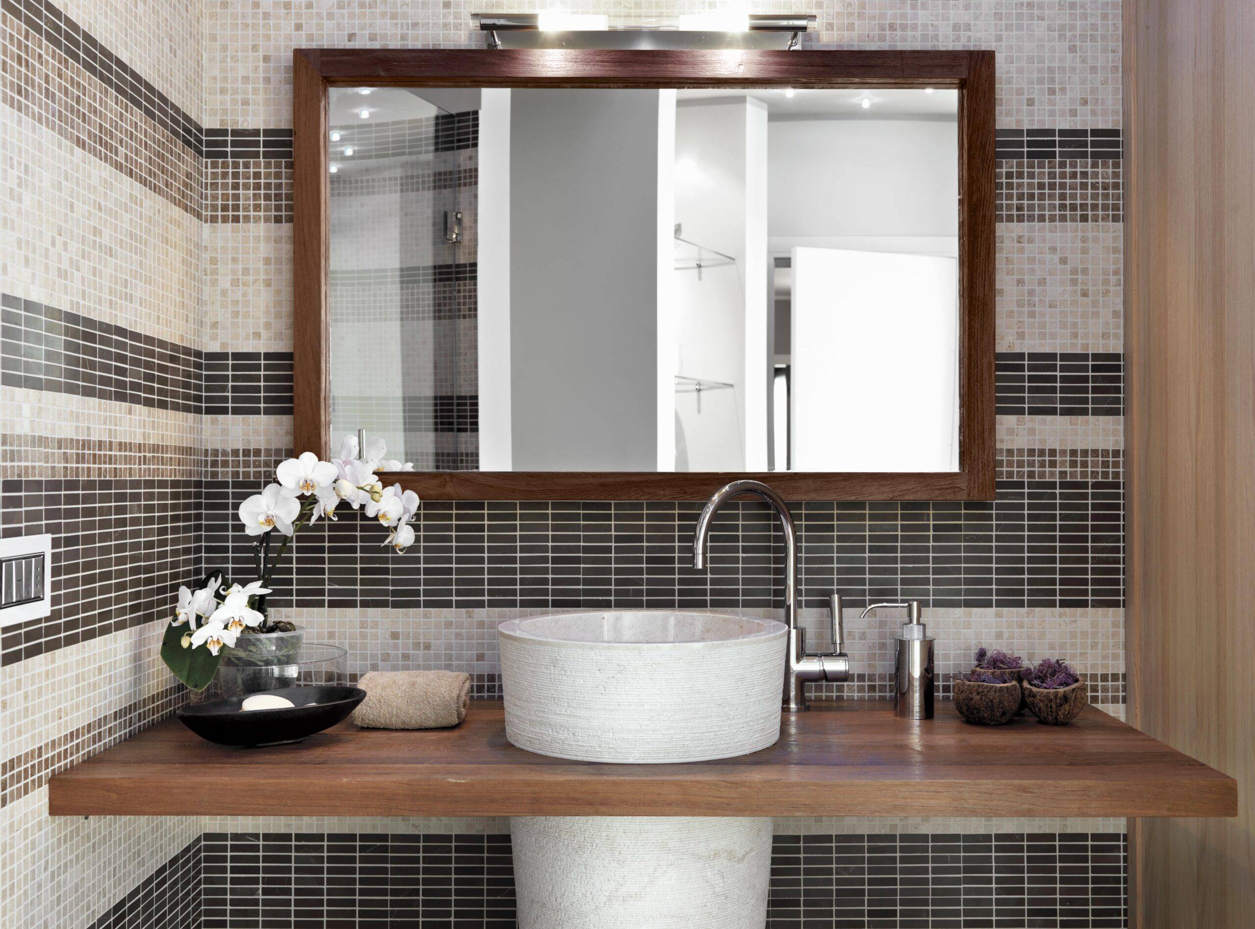 A bathroom vanity with a large, wood-framed mirror hanging above it.