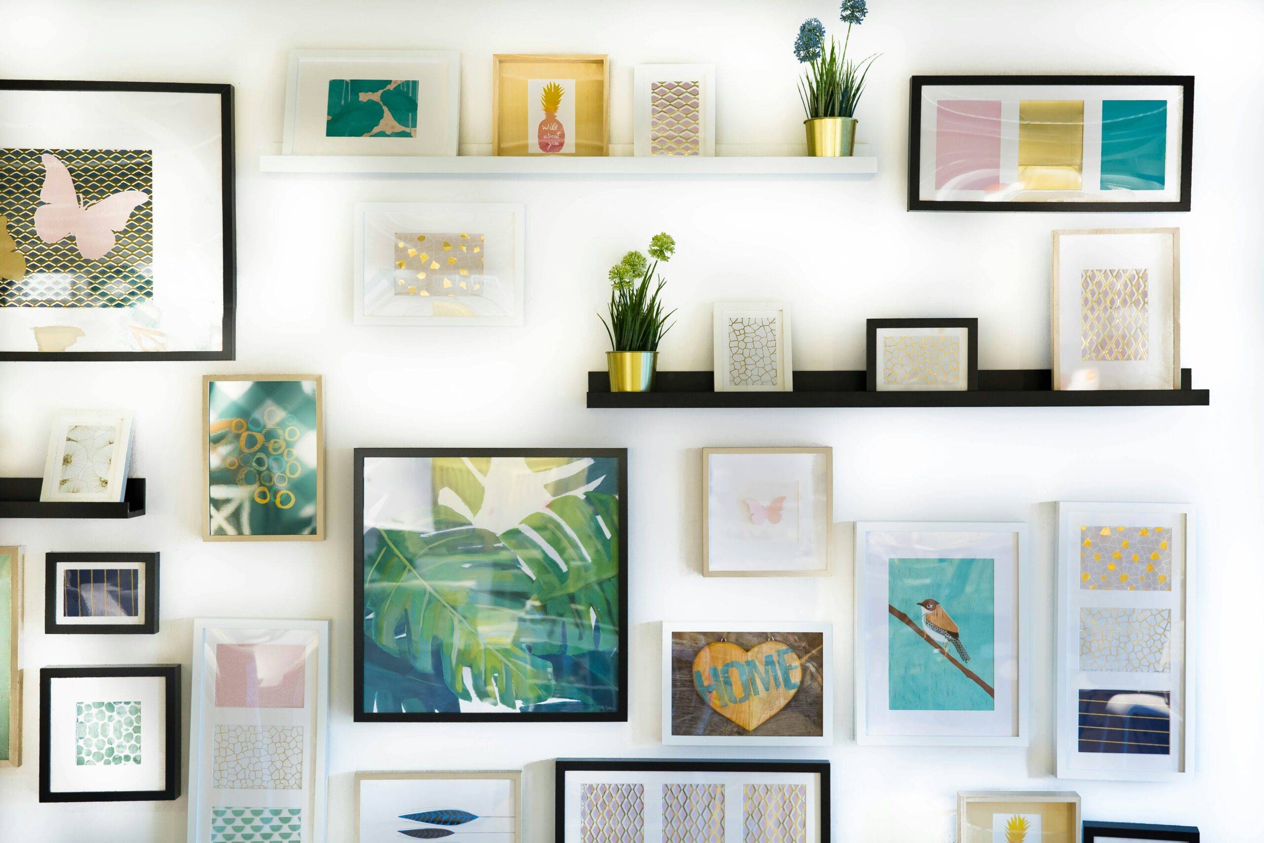 A wall covered with framed art and shelves with small items.