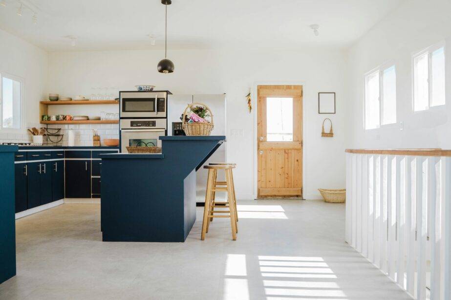 A large white kitchen with a navy blue island and cabinets.