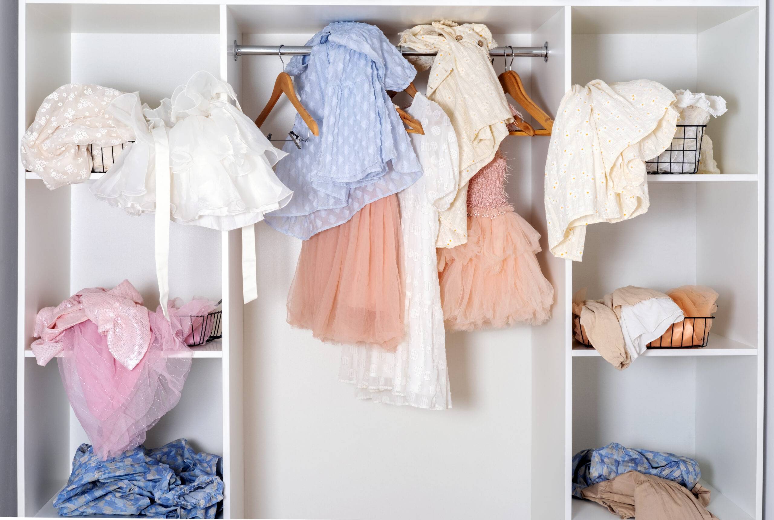 Messy dressing room shelves with stack of clothes.