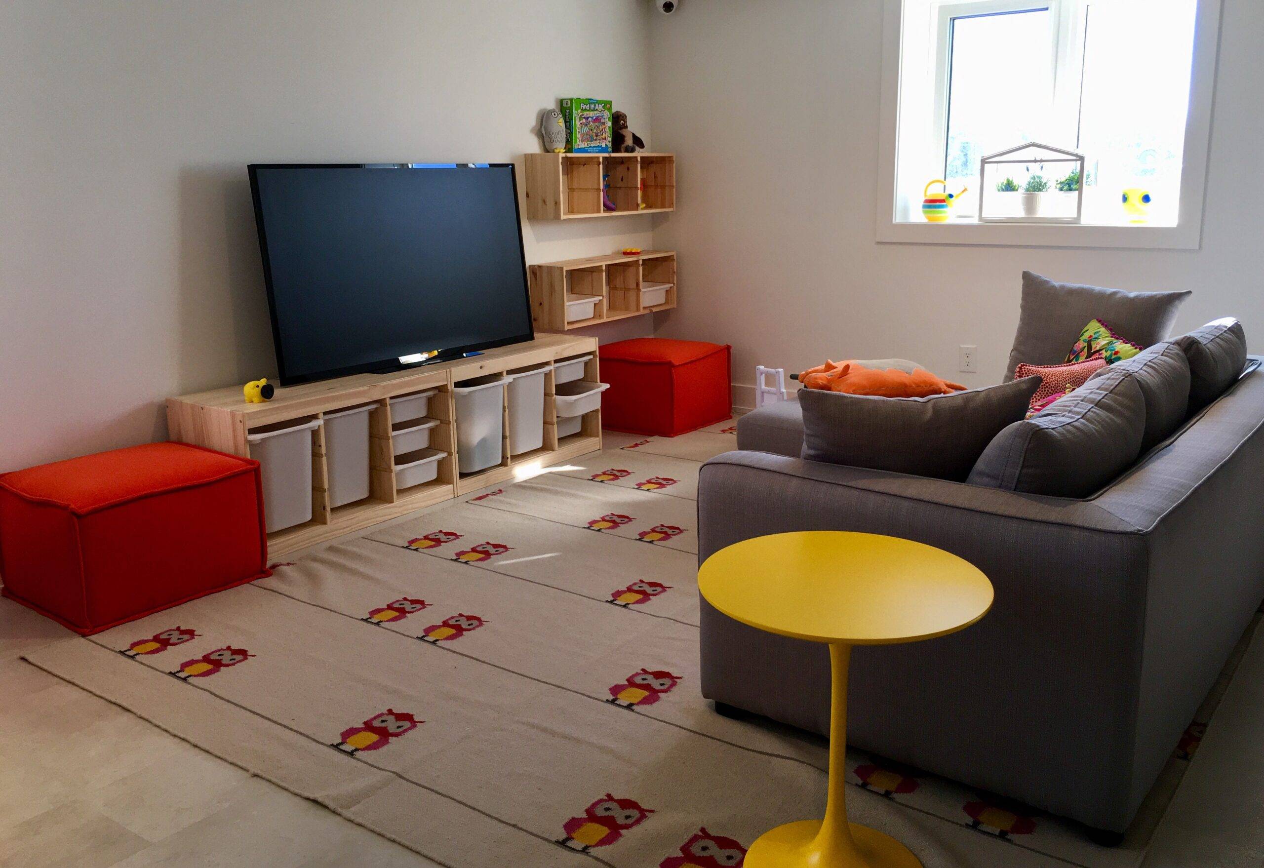 A modern, colourful living room with kid-friendly bin storage beneath the TV.