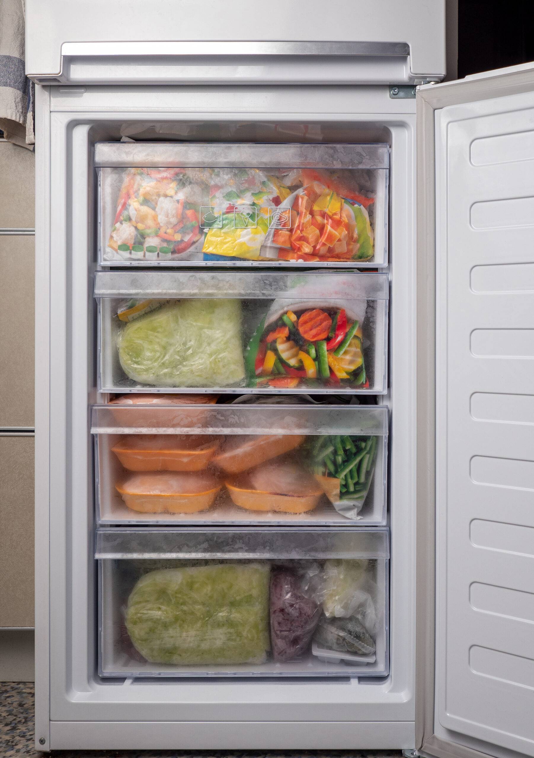 A freezer door open, full of food.