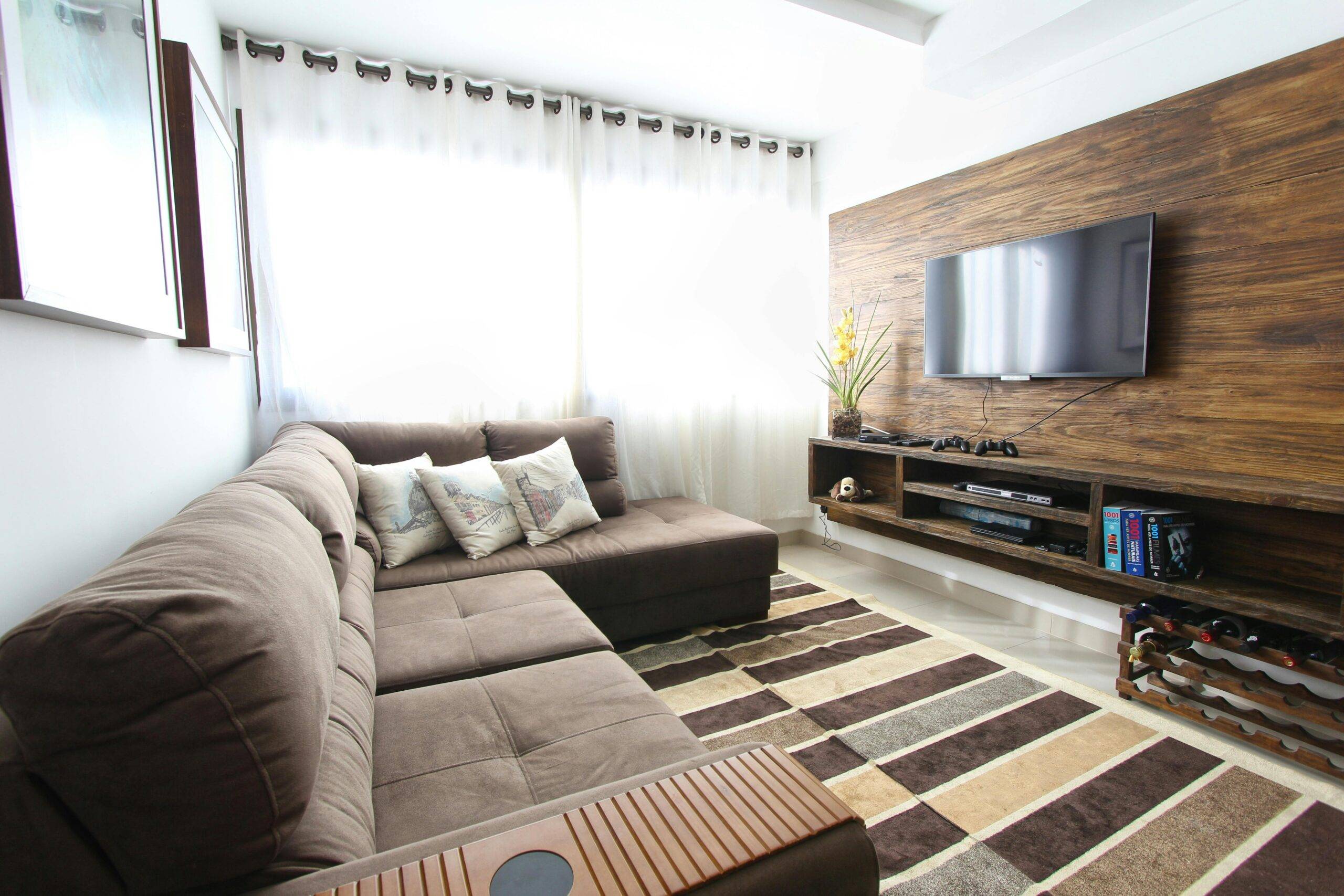 A modern living room with wood panelling behind the wall-mounted TV.