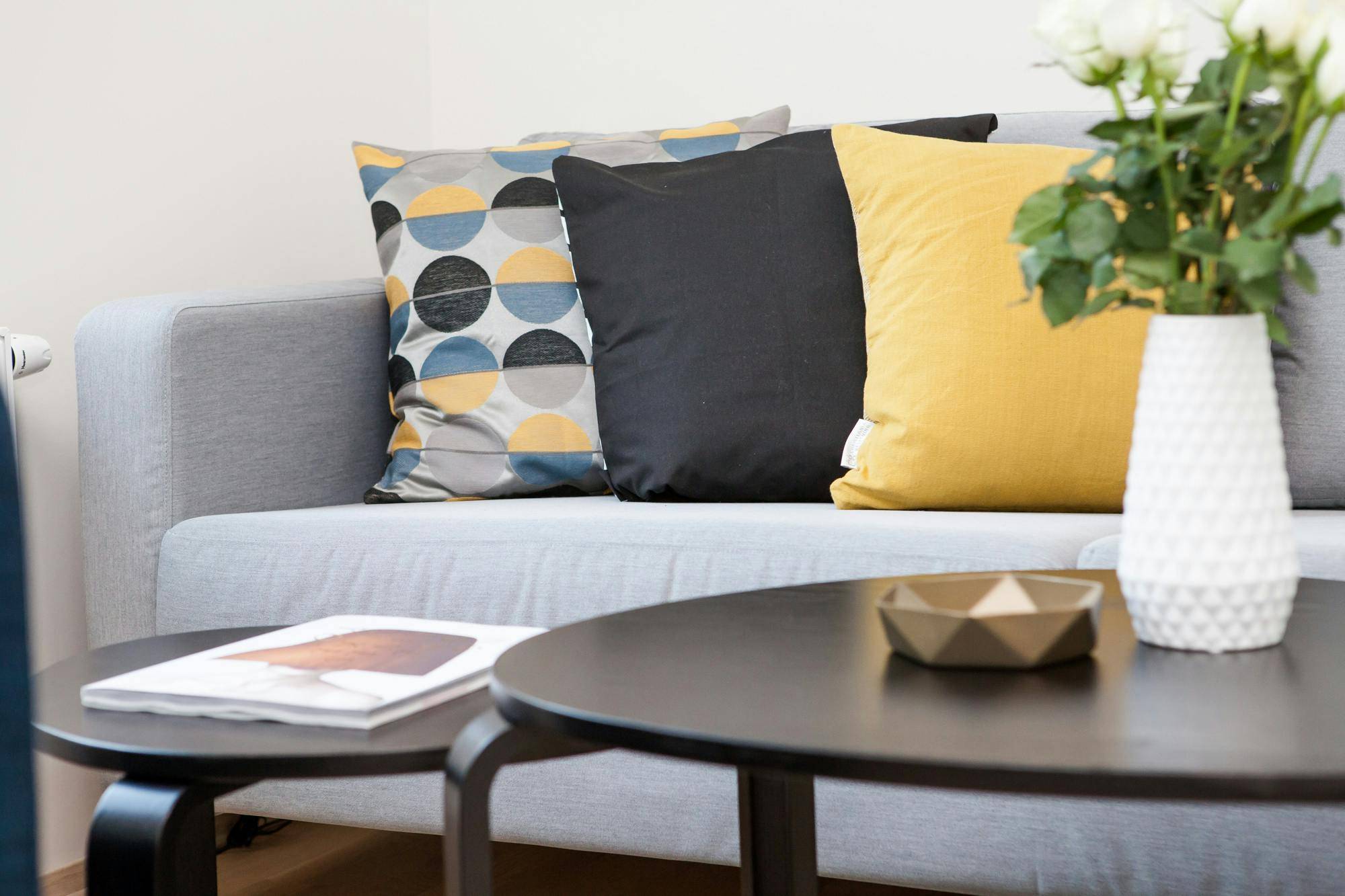 Three throw pillows on a grey couch behind a coffee table.