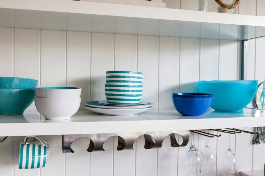 Open kitchen shelving with blue and white dishware stacked through it.